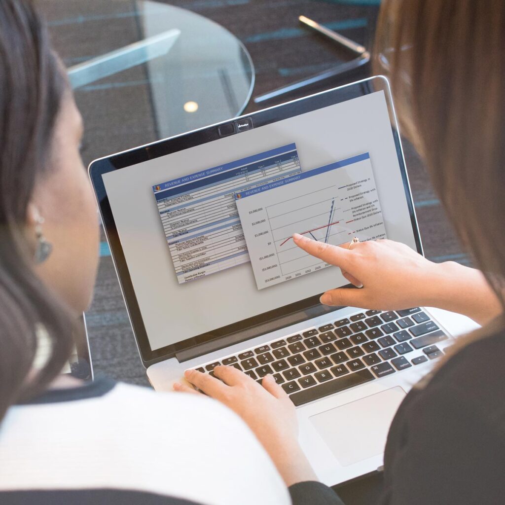 employees pointing to graph on laptop